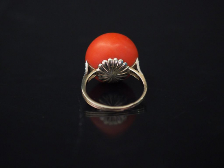 Bague en or blanc, sertie d'une boule de corail épaulée d'une ligne de