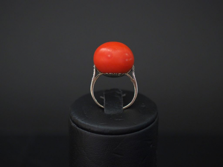 Bague en or blanc, sertie d'une boule de corail épaulée d'une ligne de