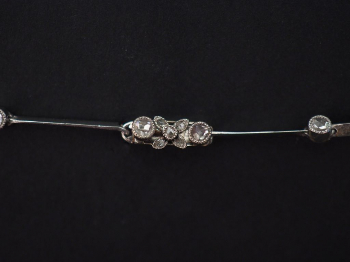 Collier articulé en en platine, à décor en son centre de fleurs et bra