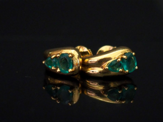 Vente aux enchères Paire de perce-oreilles en or jaune, sertis de deux émeraudes dont une