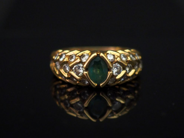 Bague jonc en or jaune, sertie en son centre d'une émeraude, entourée 