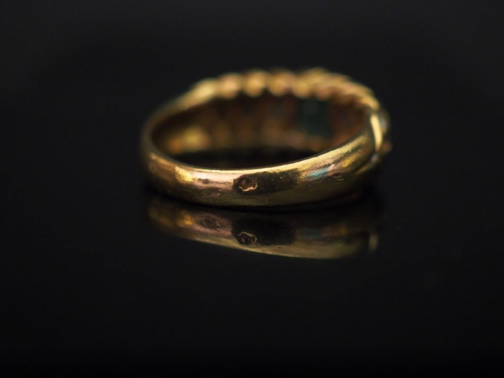 Bague jonc en or jaune, sertie en son centre d'une émeraude, entourée 