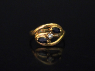 Vente aux enchères 	Bague de forme stylisée en or jaune, sertie de deux pierres bleues en