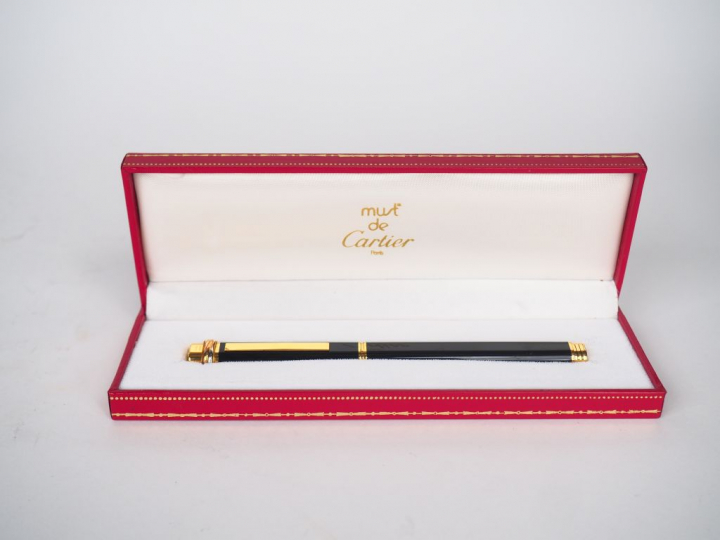 CARTIER, Must de. Stylo bille en résine noir et plaqué or.  Signé. Num