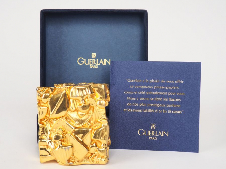 GUERLAIN. Presse-papier en plaqué or, à décor des flacons de parfum le