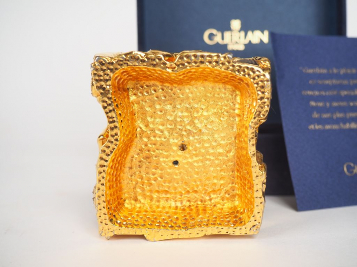 GUERLAIN. Presse-papier en plaqué or, à décor des flacons de parfum le