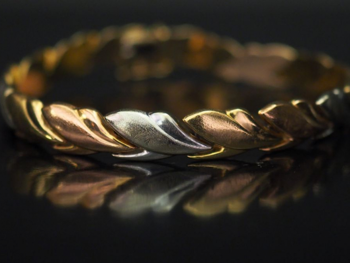 Bracelet articulé trois tons d’or, à décor de frise de feuillage. Long