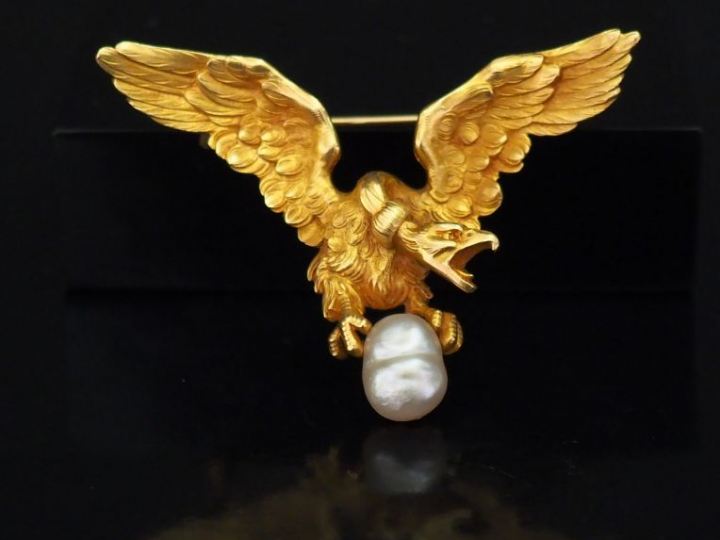 Broche en or jaune figurant un aigle aux ailes déployées tenant entre 