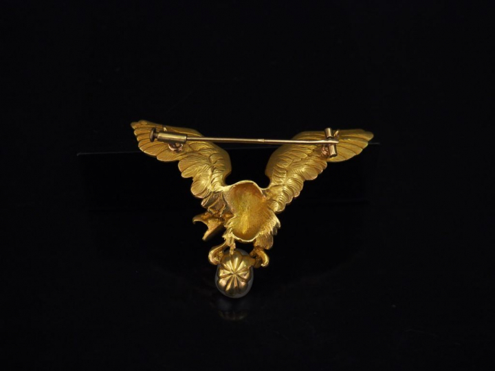 Broche en or jaune figurant un aigle aux ailes déployées tenant entre 