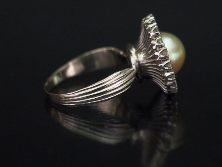 Bague ronde en or blanc, sertie en son centre d'une perle blanche ento