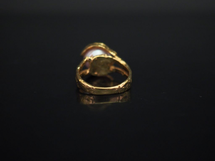 Bague de forme stylisée en or jaune, sertie en son centre d'une perle 