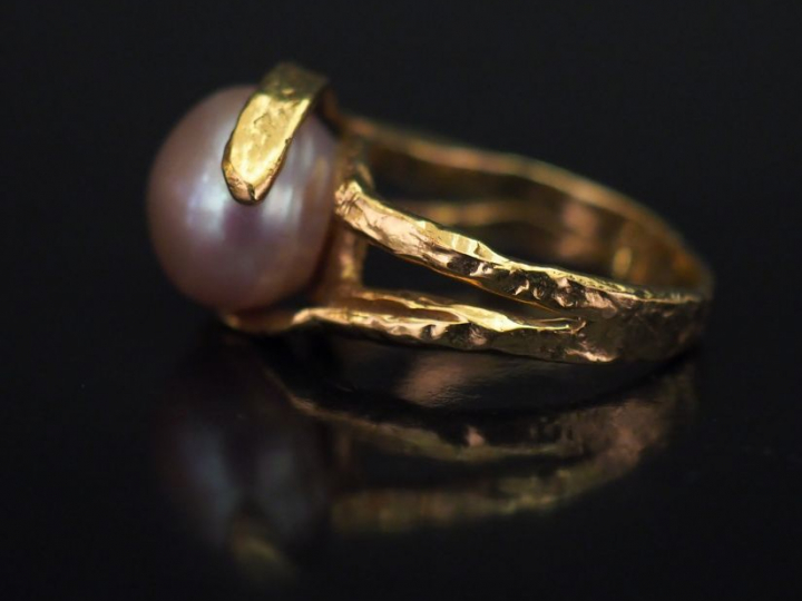 Bague de forme stylisée en or jaune, sertie en son centre d'une perle 