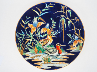 Vente aux enchères LONGWY. Plat rond en émaux polychromes. "murmure" Diam. 36 cm (éclat)