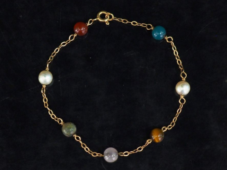 Vente aux enchères Bracelet souple en or jaune, perles blanches et pierres dures. Long. 1