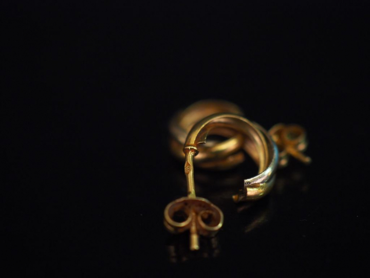 Paire de demi-créoles deux tons d'or, à décor de motifs torsadés. H. 1