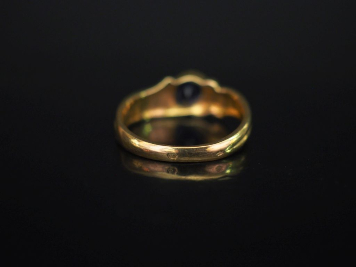 Bague en or jaune, sertie en son centre d'une pierre bleue en forme de