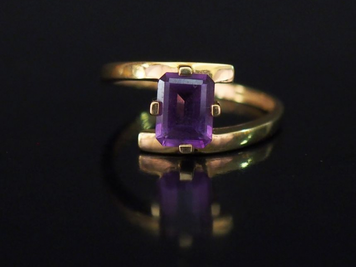 Bague de forme stylisée en or jaune, sertie d'une pierre mauve. TDD. 6