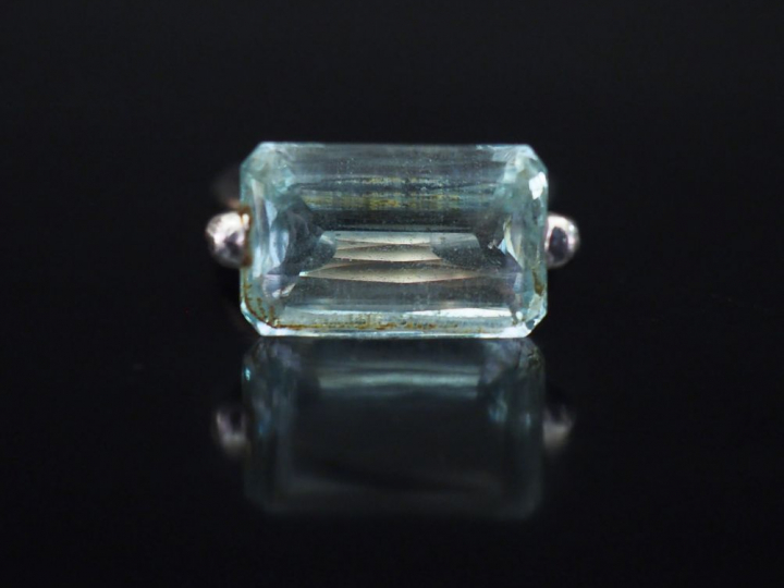 Bague en or blanc, sertie en son centre d'une pierre bleu ciel épaulée