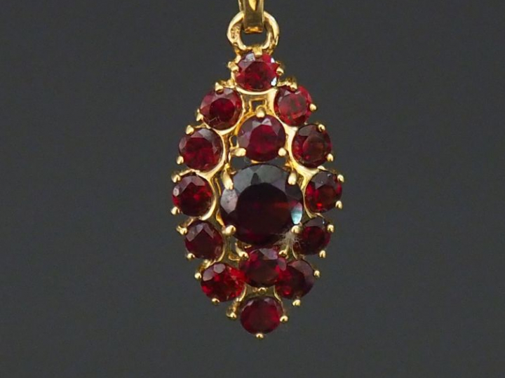 Pendentif de forme ovale en or jaune, serti de grenats. H. 2 cm Poids 
