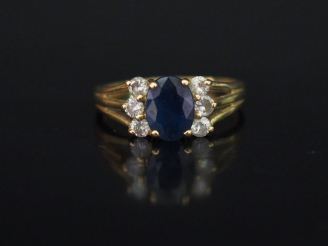 Vente aux enchères Bague en or jaune 14k, sertie en son centre d'une pierre bleue épaulée