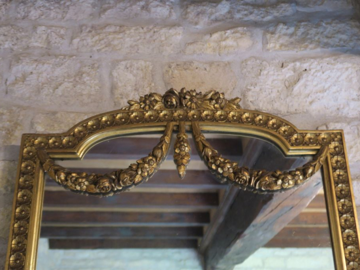 Miroir de style Louis XVI en bois et stuc doré, à décor de frise de fl