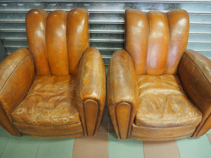 Paire de fauteuils club en cuir brun. (usures)