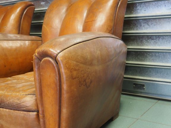 Paire de fauteuils club en cuir brun. (usures)