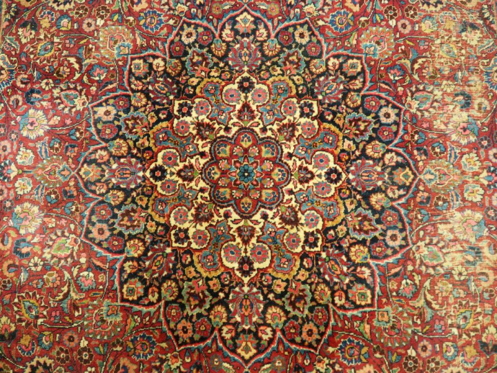 Grand tapis d'Orient en laine, à décor fleuri sur fond lie de vin. Dim