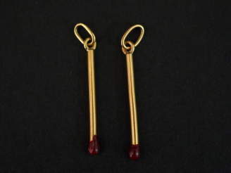 Vente aux enchères Deux pendentif en or jaune et émail rouge, en forme d'allumettes. H. 2