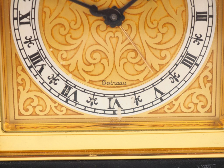 LUXOR. Pendulette de table en laiton, cadran à décor de rinceaux. Sign