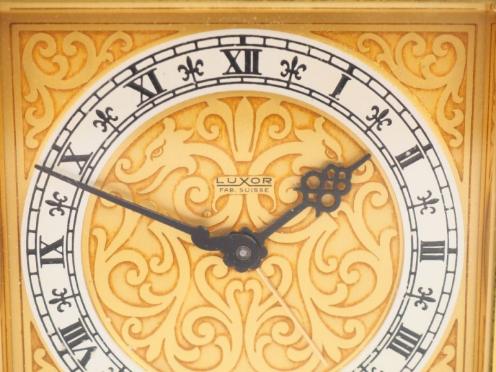 LUXOR. Pendulette de table en laiton, cadran à décor de rinceaux. Sign