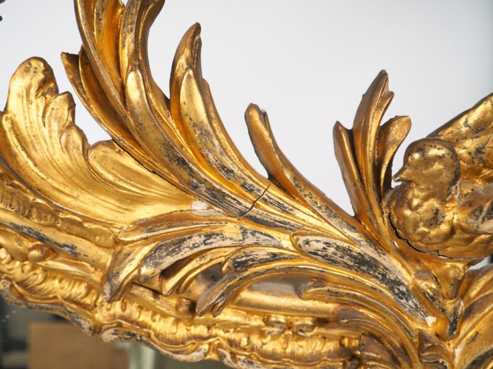 Miroir Louis XV en bois et stuc doré à décor feuillagé, surmonté d'un 