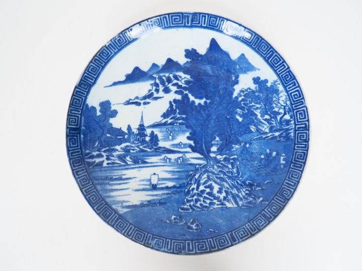 Plat en porcelaine à décor au pochoir en camaïeu de bleu d'un paysage 