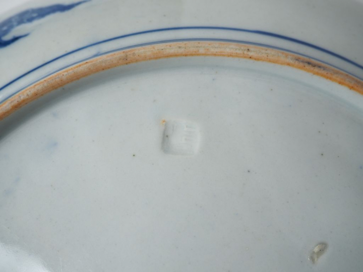 Plat en porcelaine à décor au pochoir en camaïeu de bleu d'un paysage 