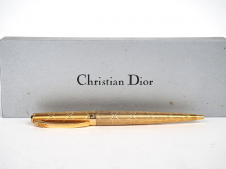 Vente aux enchères CHRISTIAN DIOR. Stylo à bille en métal plaqué dans son coffret. Signé.