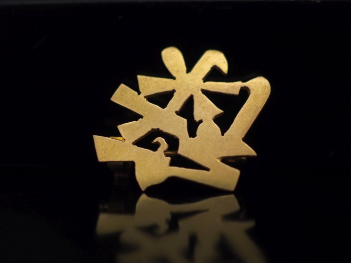 Petite broche en or jaune en forme de caractère.  1,9 x 2,1 cm Poids. 