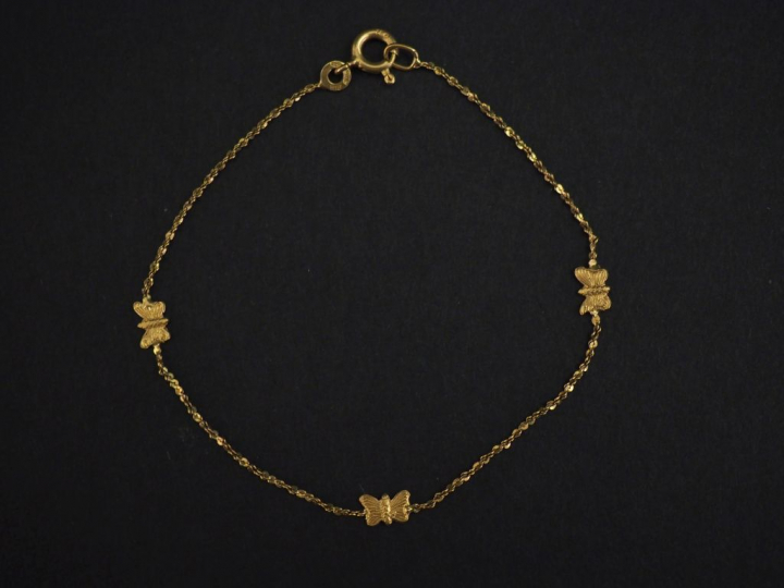Petit bracelet souple en or jaune, à décor de papillons.  Travail ital