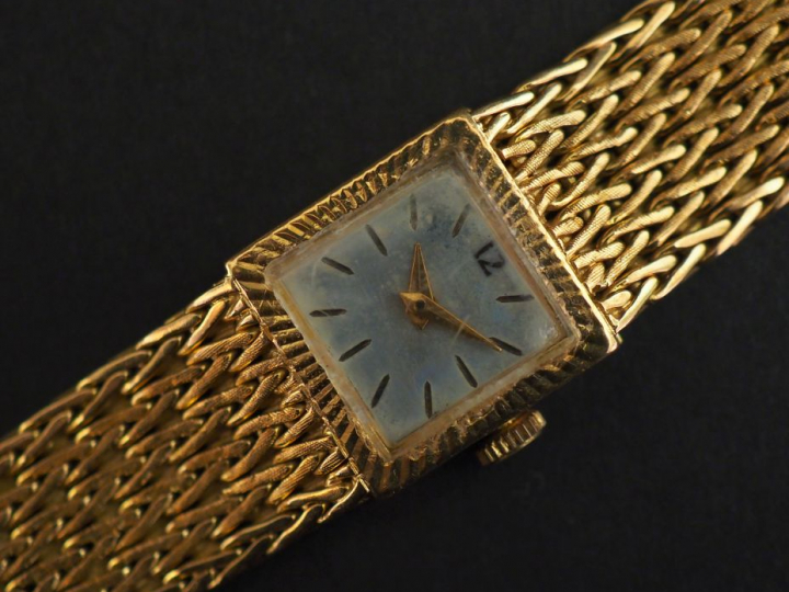 Montre bracelet, boitier et bracelet en or jaune.  Cadran carré à moti