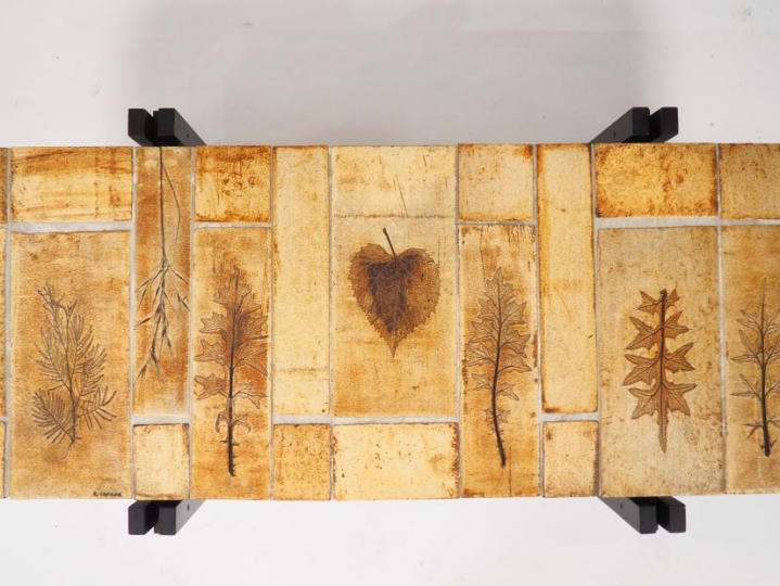 CAPRON.  Table basse, plateau en céramique à décor de feuilles, piétem