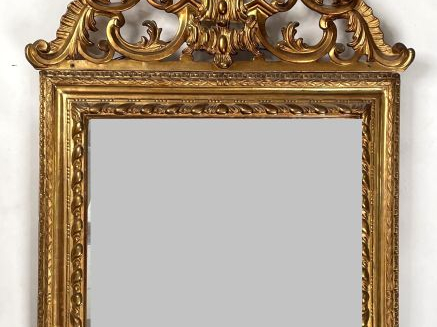 Glace Louis XVI en bois et stuc doré à décor de feuillage et de godron