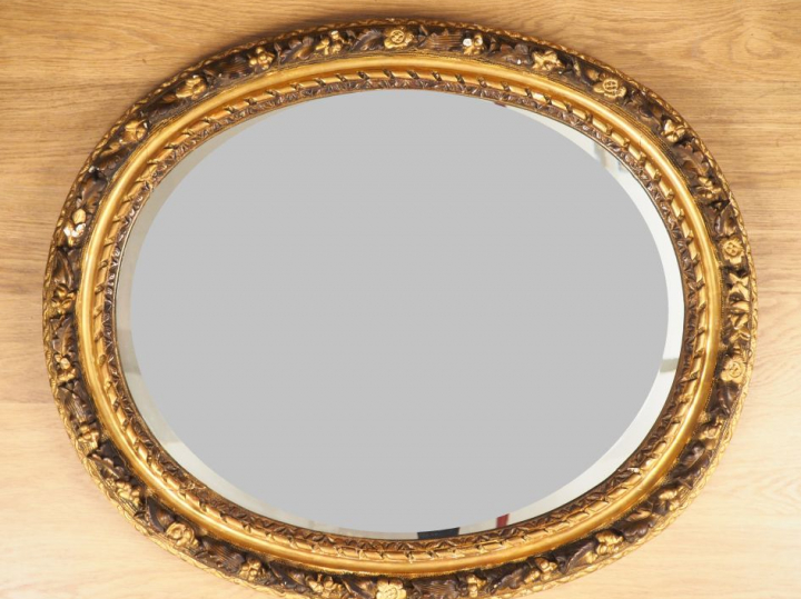 Miroir ovale, cadre Louis XVI en bois et stuc doré, à décor de fleurs 