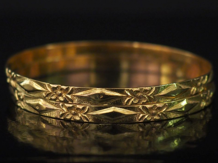 Paire de bracelets joncs, à décor de fleurs et losanges alternés. Diam