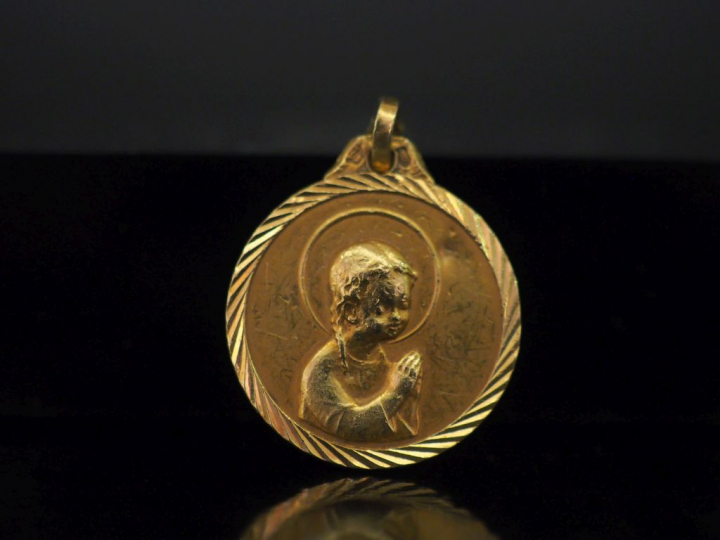 Médaille religieuse en or jaune, figurant une jeune sainte en prière l