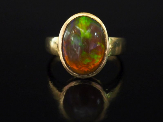 Vente aux enchères Bague en or jaune, sertie en son centre d'une pierre dure en cabochon.