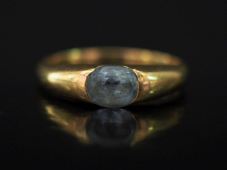 Vente aux enchères Bague jonc en or jaune, sertie en son centre d'une pierre bleu ciel. T