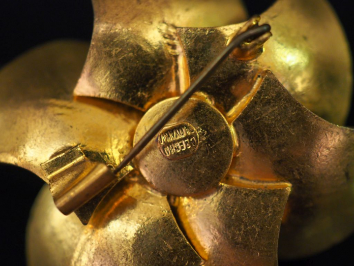 Broche en métal doré et pierres fantaisie bleu ciel en forme de fleur.