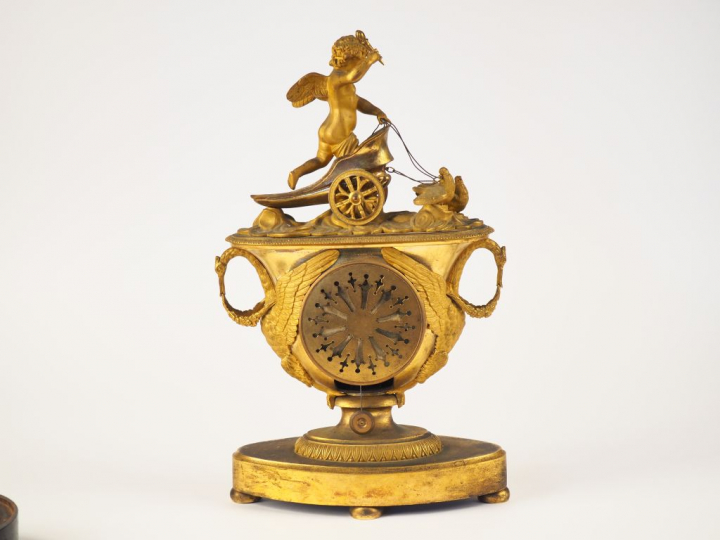 Pendule de cheminée Empire en bronze ciselé et doré "l'amour sur son c
