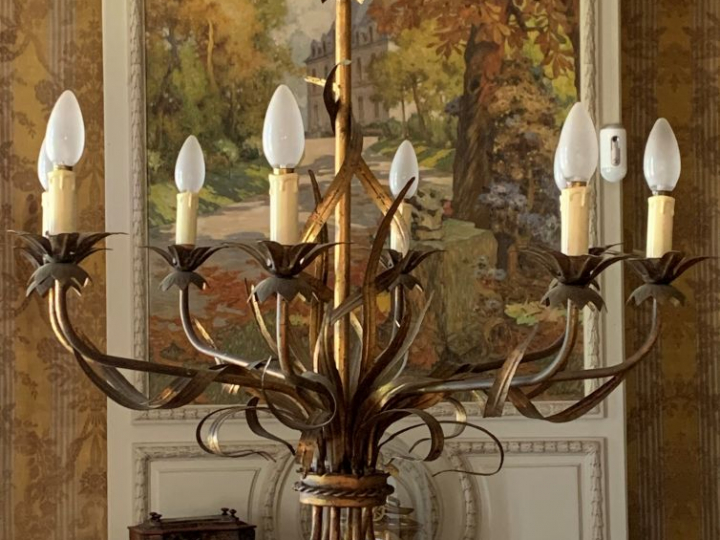 Lustre en tôle dorée éclairant à huit lumières à décor de feuillage.