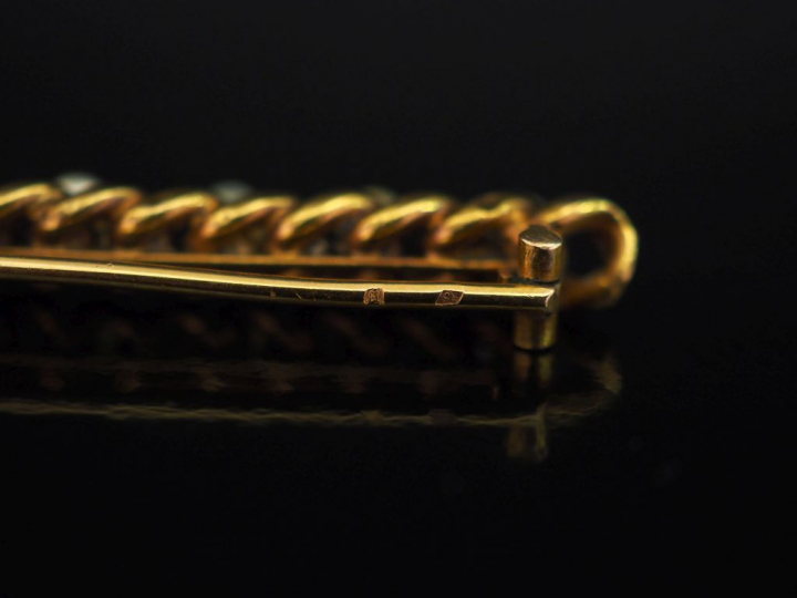 Ensemble comprenant :  - une broche barrette ajourée en or jaune 750, 