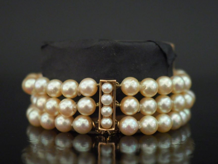 Bracelet manchette trois rangs de perles blanches.  Fermoir et chainet